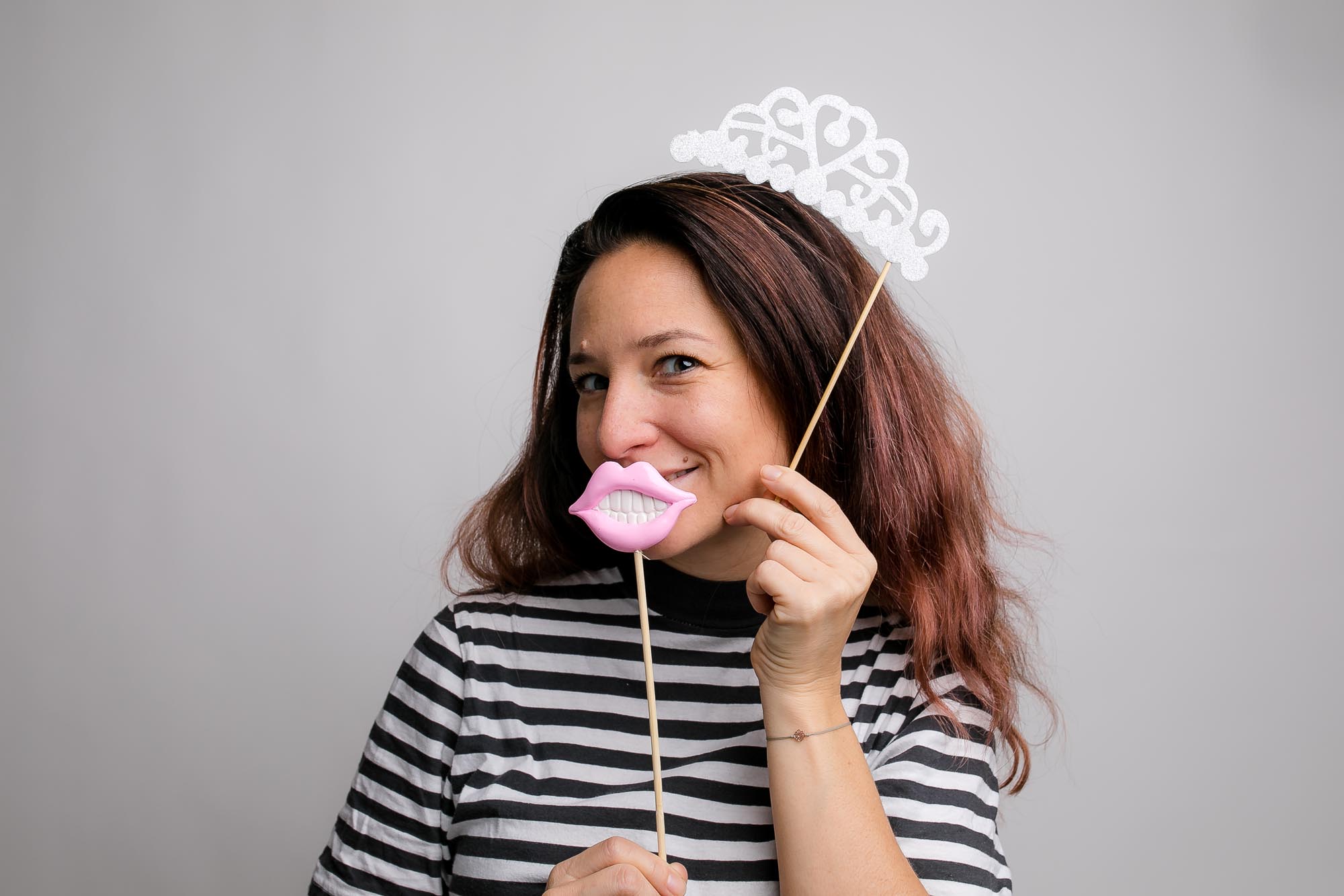 Eine Person mit Federboa und glitzernder Partybrille macht eine lustige Pose vor der Fotobox.