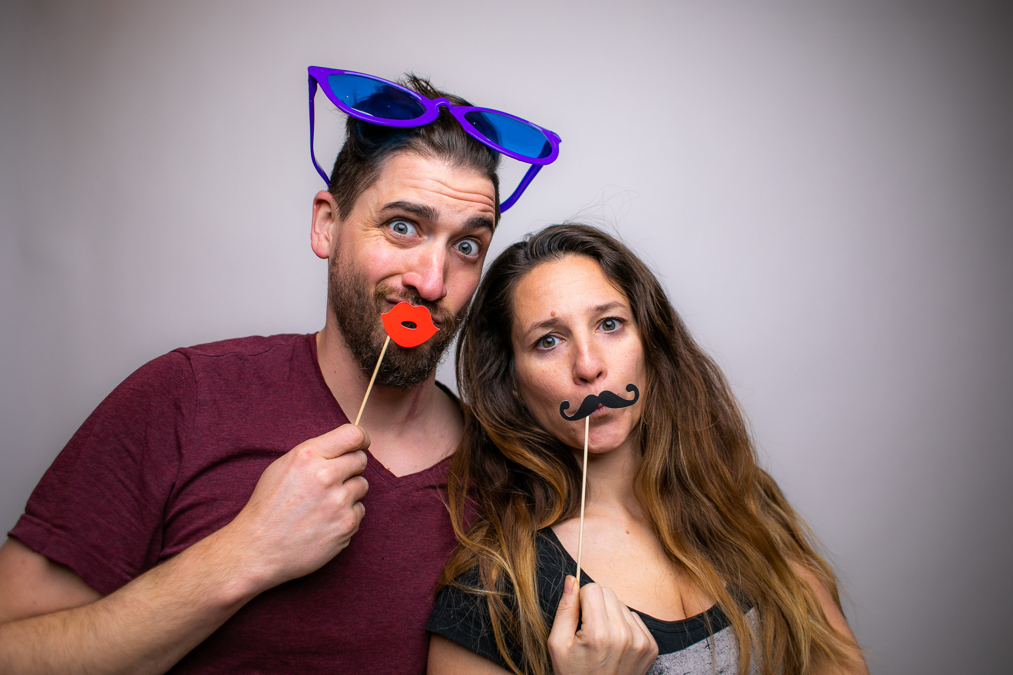 Eine Person mit bunter Perücke und Sternbrille schaut lachend in die Fotobox-Kamera.