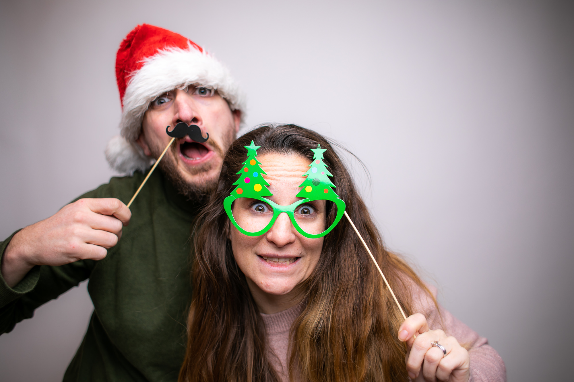 Eine Person mit übergroßer Sonnenbrille und Hut hält ein Spaßschild vor der Fotobox.