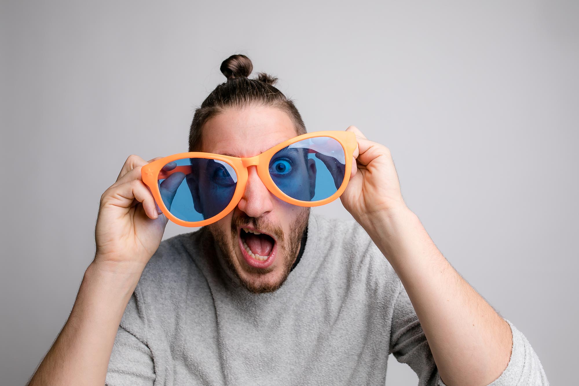 Eine Person mit Hippie-Perücke und runder Sonnenbrille lächelt vor der Fotobox.