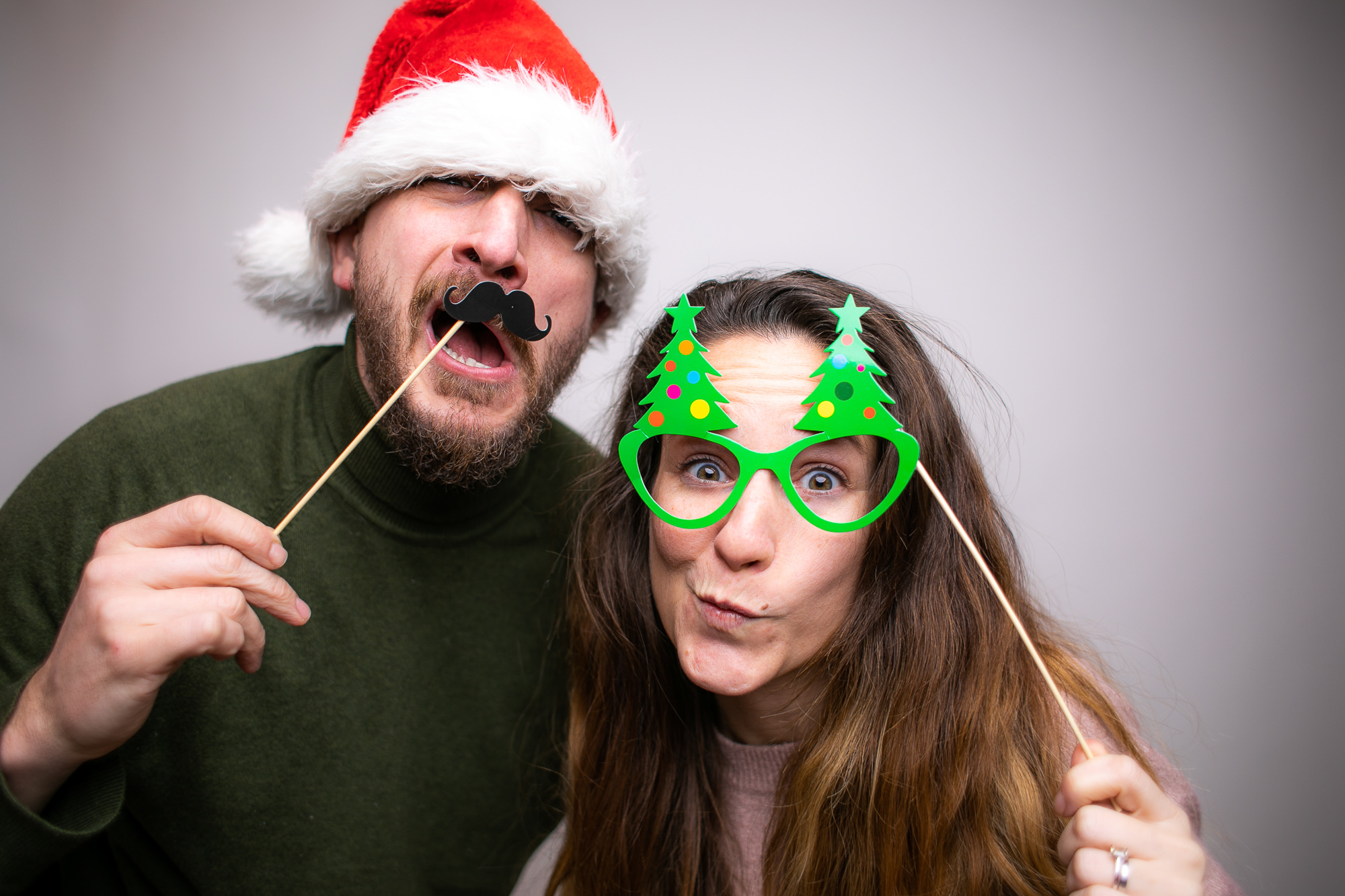 Eine Person mit Flamingo-Brille und Federboa posiert fröhlich vor der Fotobox.