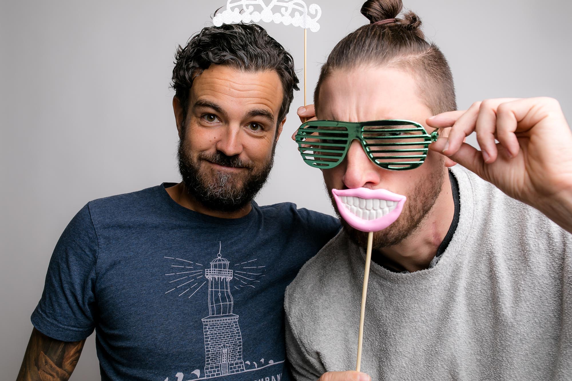 Eine Person mit Federboa und Herzbrille posiert vor der Fotobox-Kamera. Titel: Partyfotobox mit lustigen Requisiten